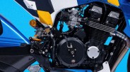 Close-up of a black motorcycle engine with visible carburetor, exhaust pipe, and blue and yellow body panels.
