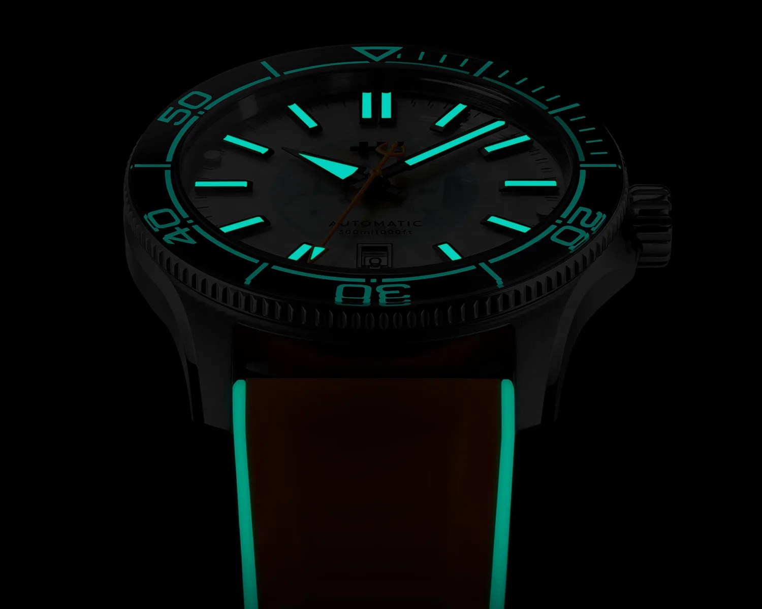 Black dive watch with glowing turquoise hour markers, hands, bezel numerals, and strap edges in darkness.
