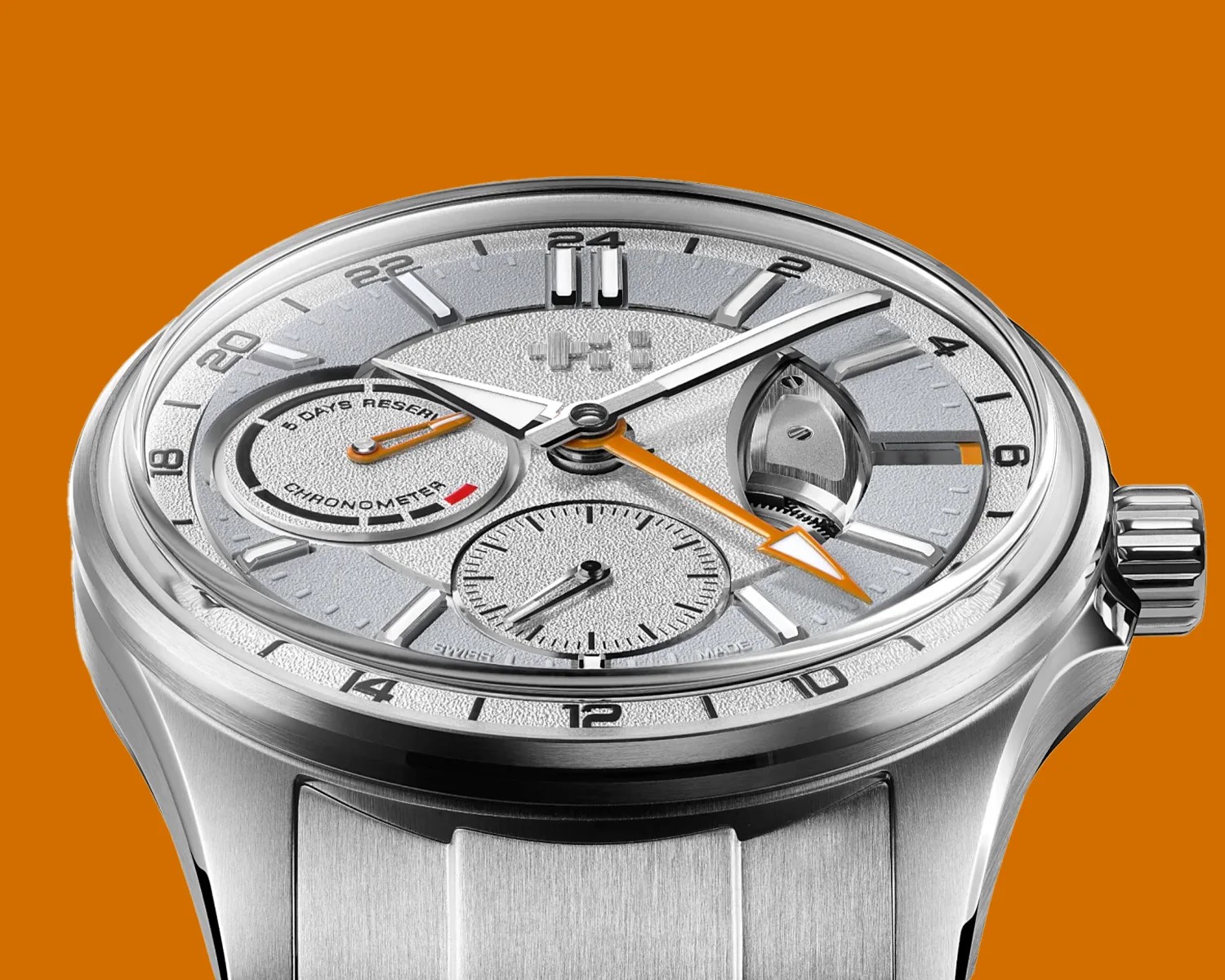 Silver chronometer wristwatch with orange-tipped hands and a brushed metal band on an orange background.