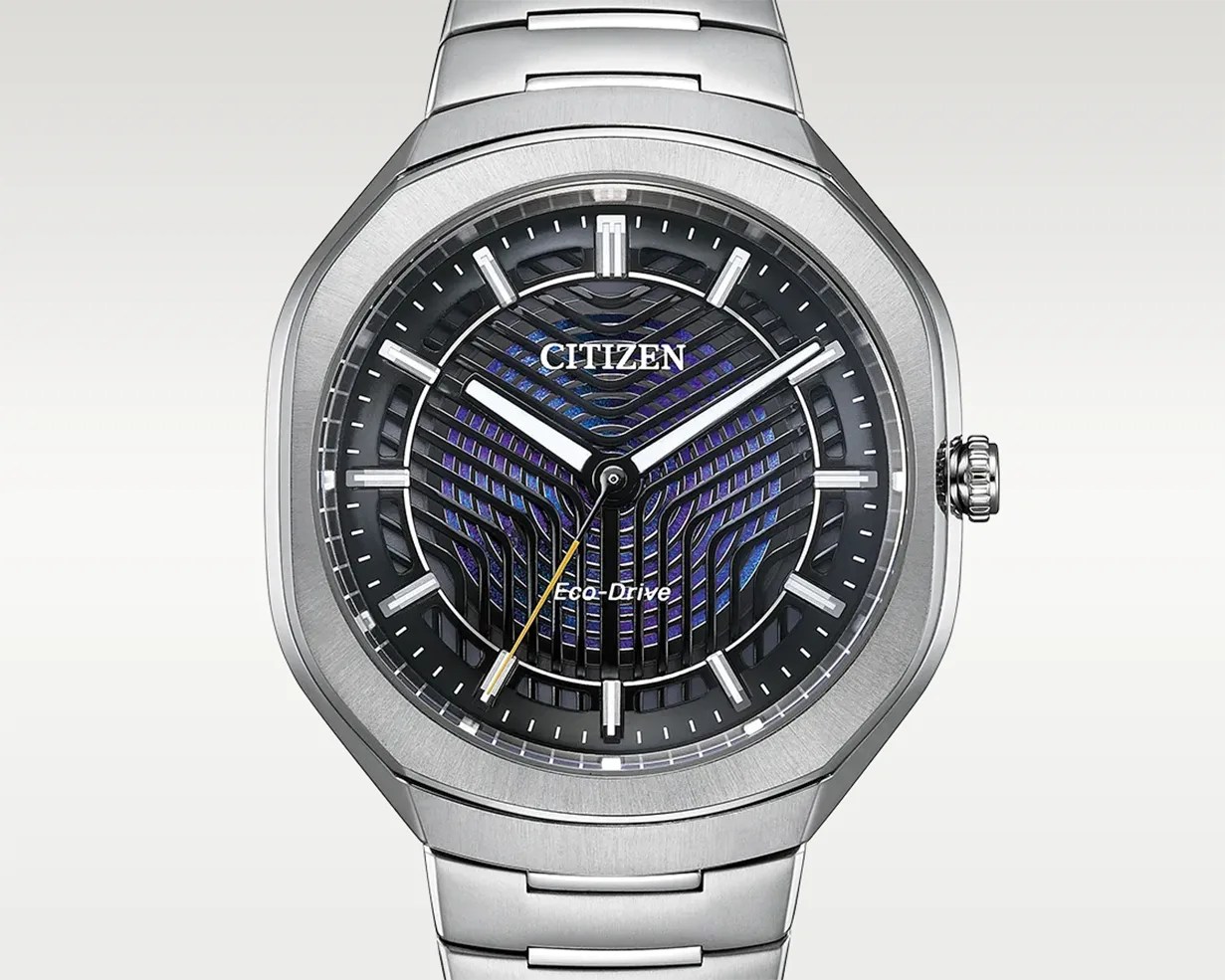 Silver Citizen Eco-Drive watch with a geometric black and blue patterned dial and a stainless steel bracelet.