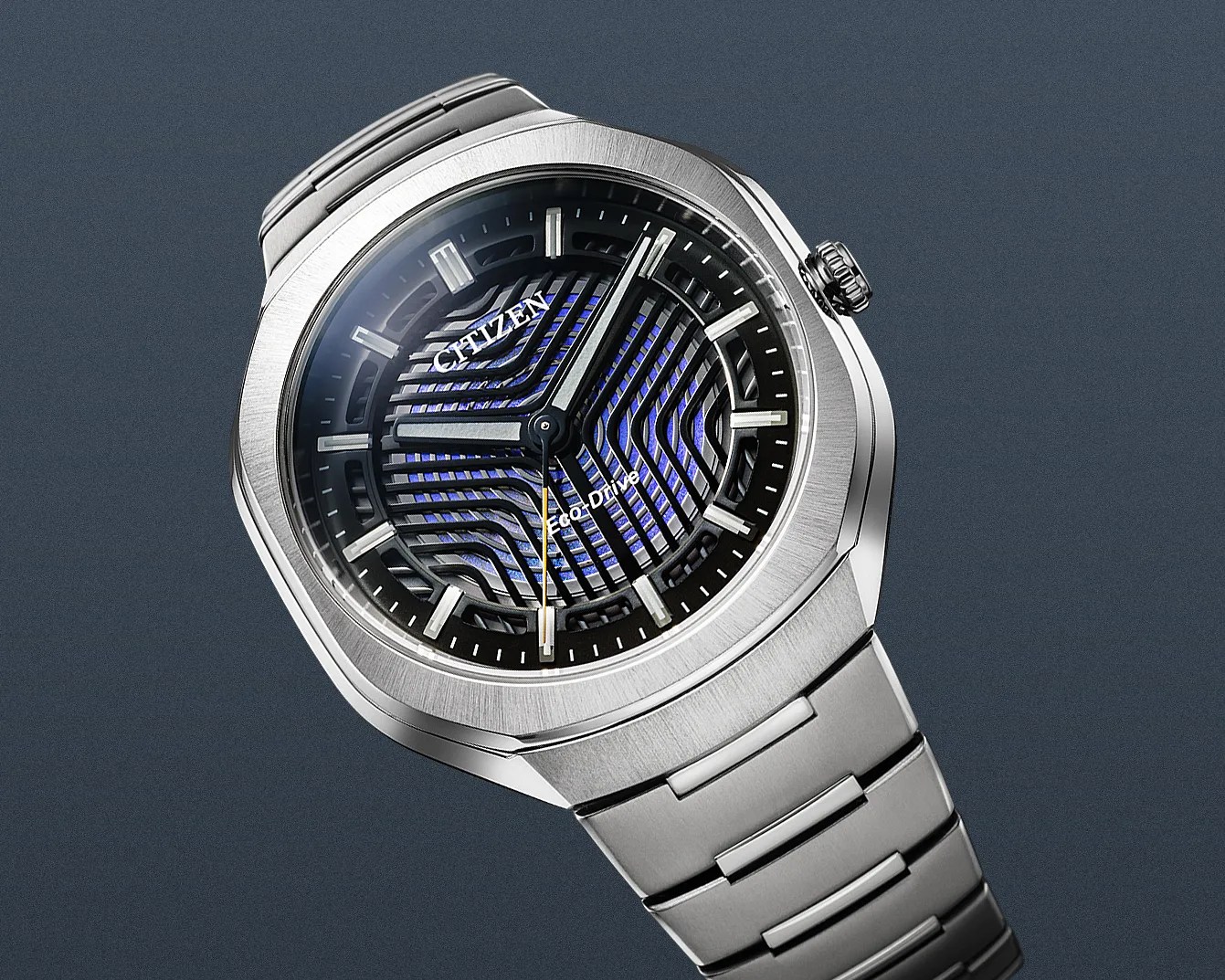 Silver Citizen Eco-Drive wristwatch with a geometric black and blue patterned dial and metal bracelet.