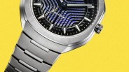 Close-up of a silver metal wristwatch with a textured black and blue dial and "Eco-Drive" text on a yellow background.