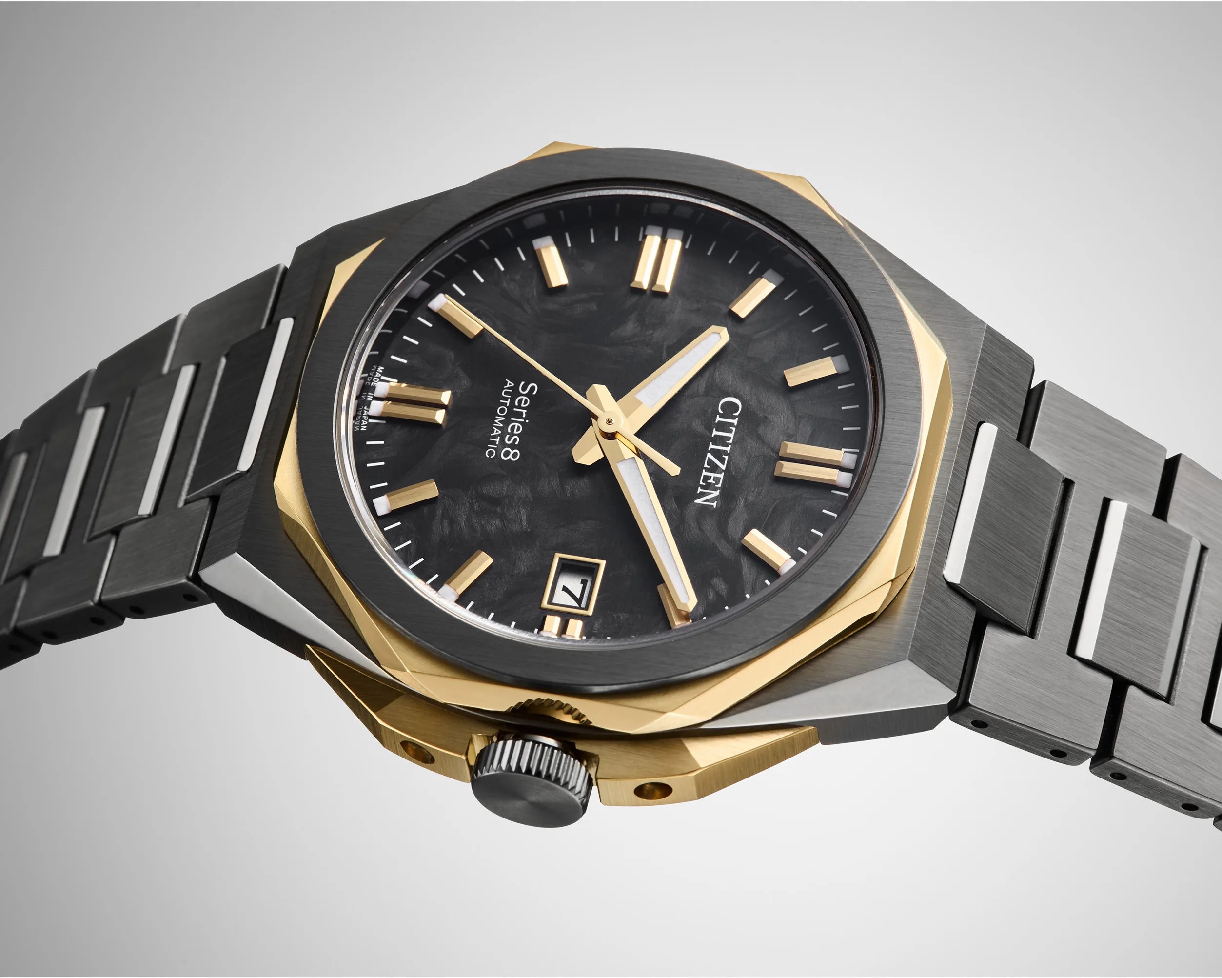 Citizen Series 8 automatic watch with black textured dial, gold-tone markers, and two-tone metal bracelet.