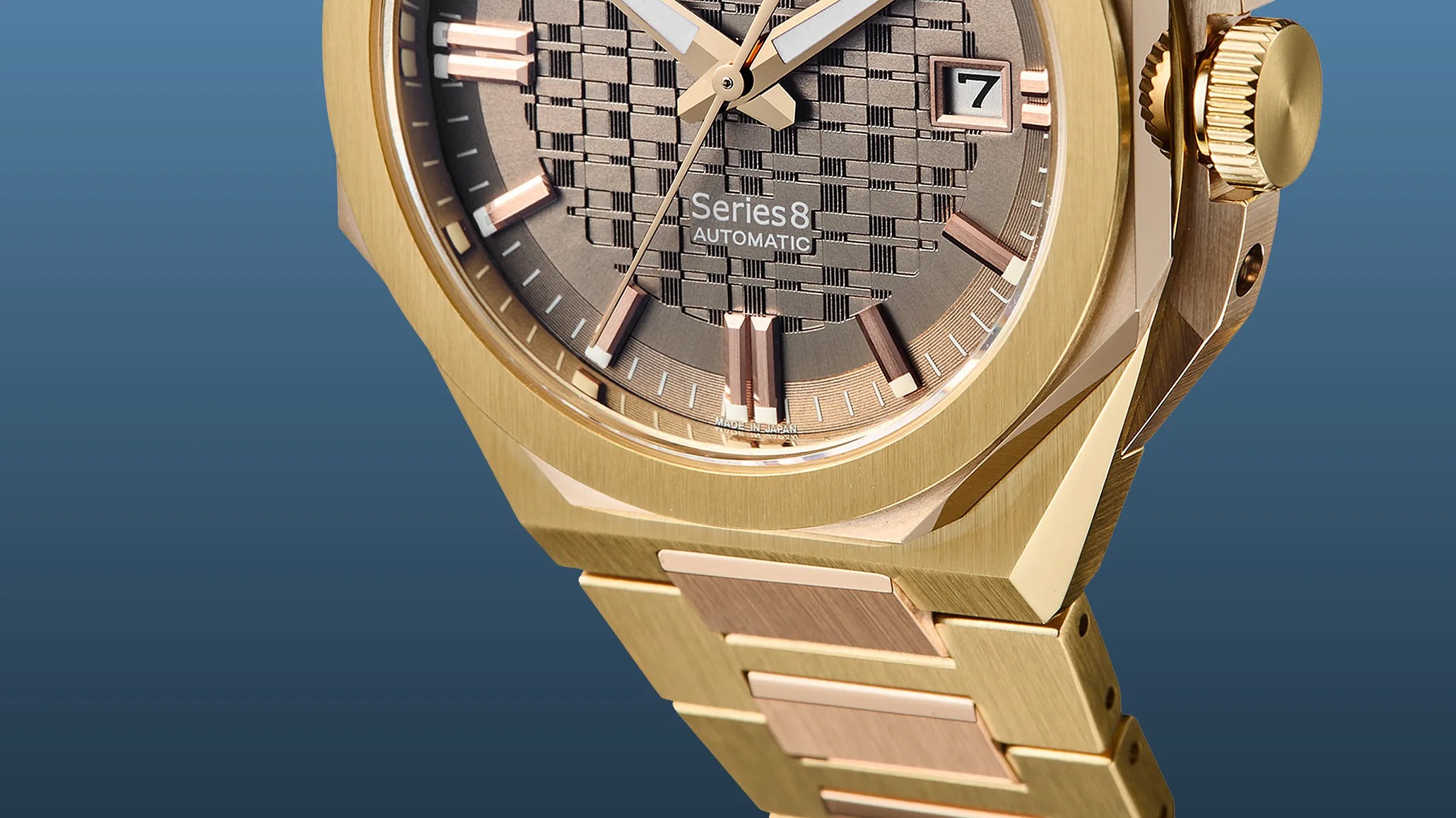 Close-up of a gold-tone Series 8 automatic wristwatch with a textured dial and date display.