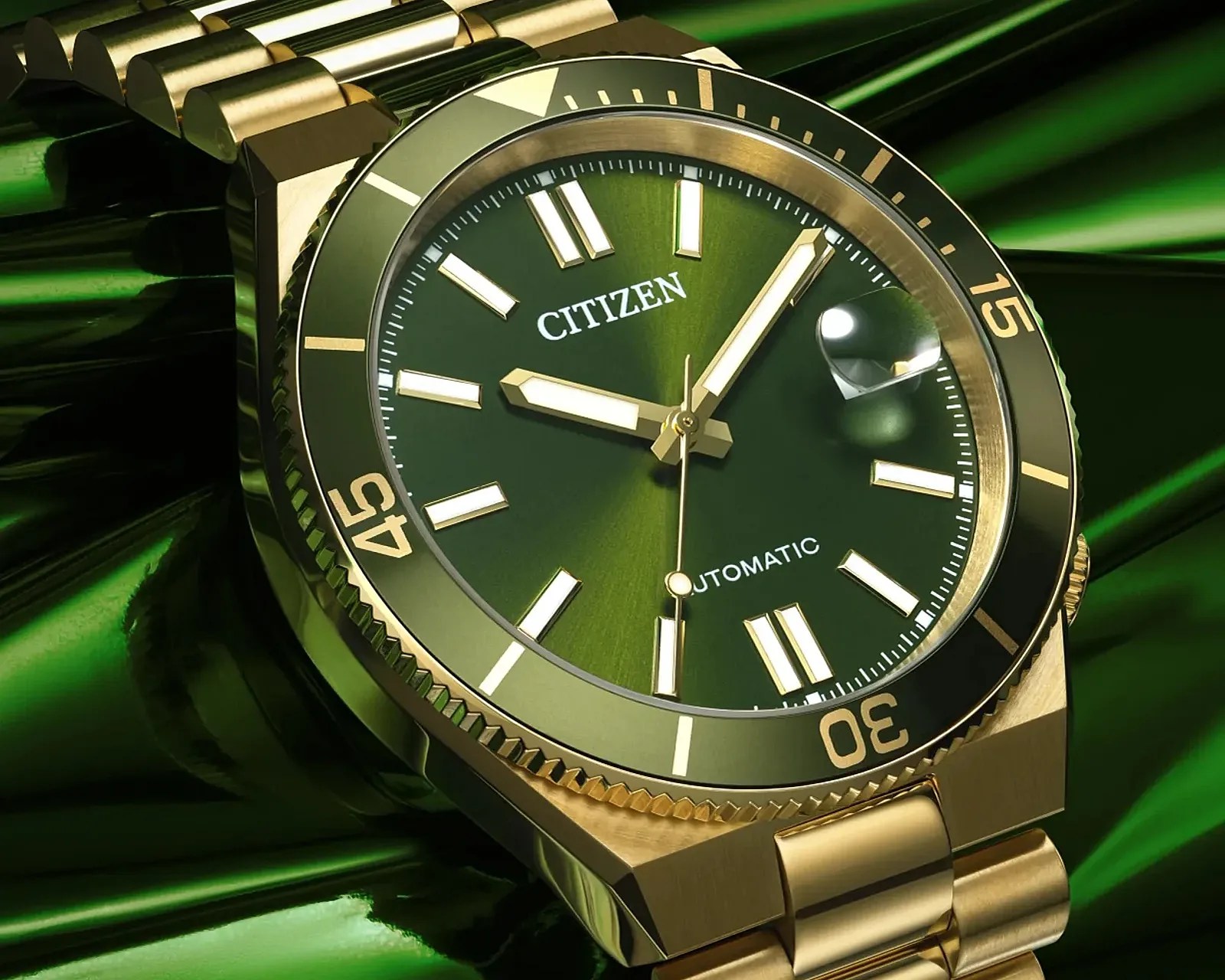 Gold-tone Citizen wristwatch with green dial, white hour markers, and rotating bezel on a green reflective surface.