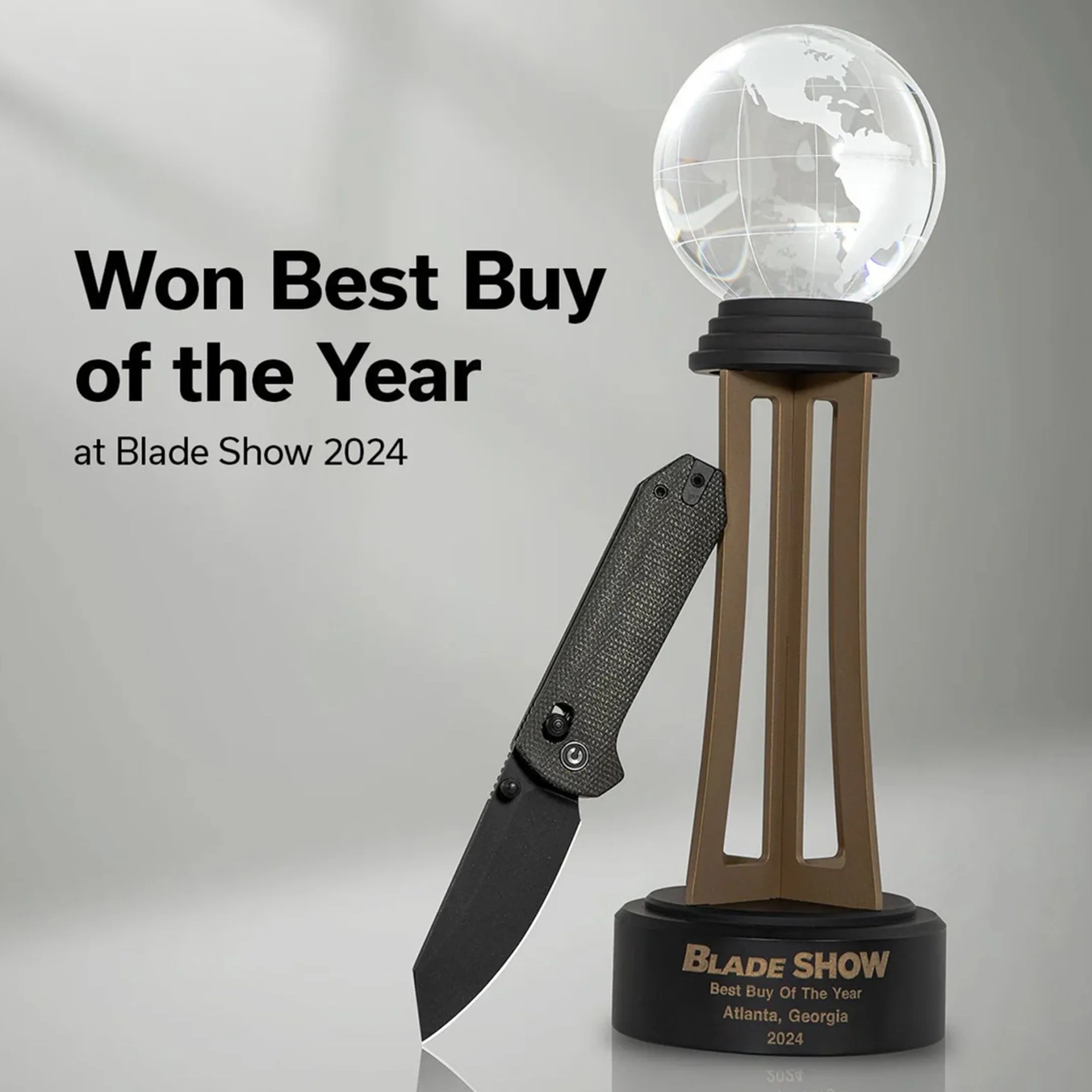 Trophy with a clear globe on top and a black and bronze base holding a black folding knife, with text "Won Best Buy of the Year at Blade Show 2024.