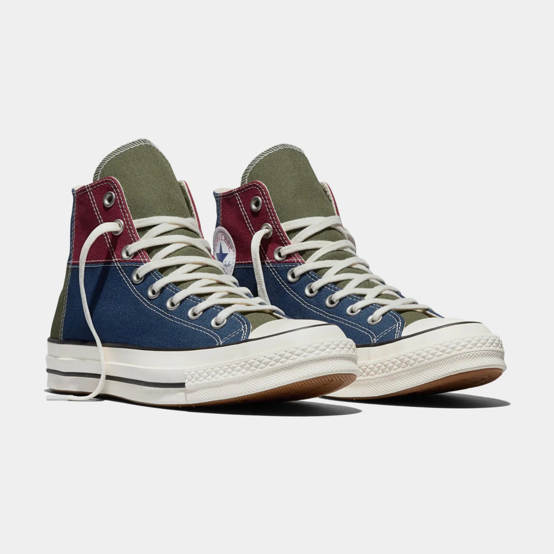 Pair of high-top Converse sneakers in olive green, navy blue, and burgundy with white laces and rubber soles.