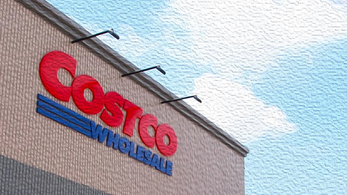 Costco Wholesale red and blue sign on a beige brick building under a partly cloudy sky.