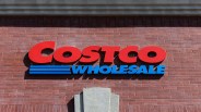 Red and blue Costco Wholesale sign mounted on a red brick wall.