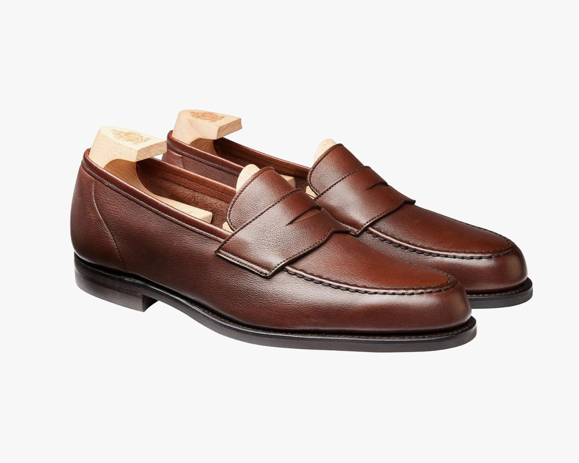 Pair of brown leather penny loafers with wooden shoe trees inside.