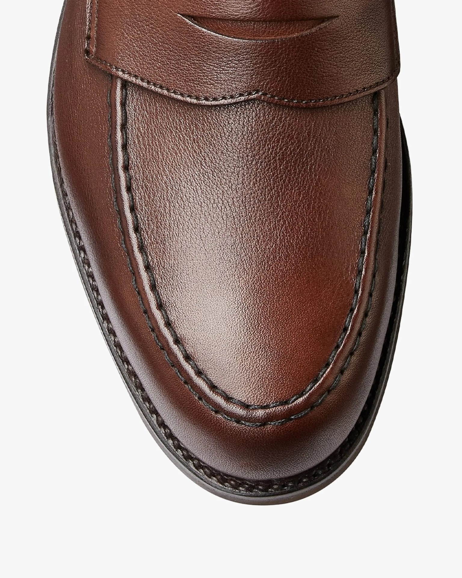Close-up of the toe area of a brown leather loafer with detailed stitching.
