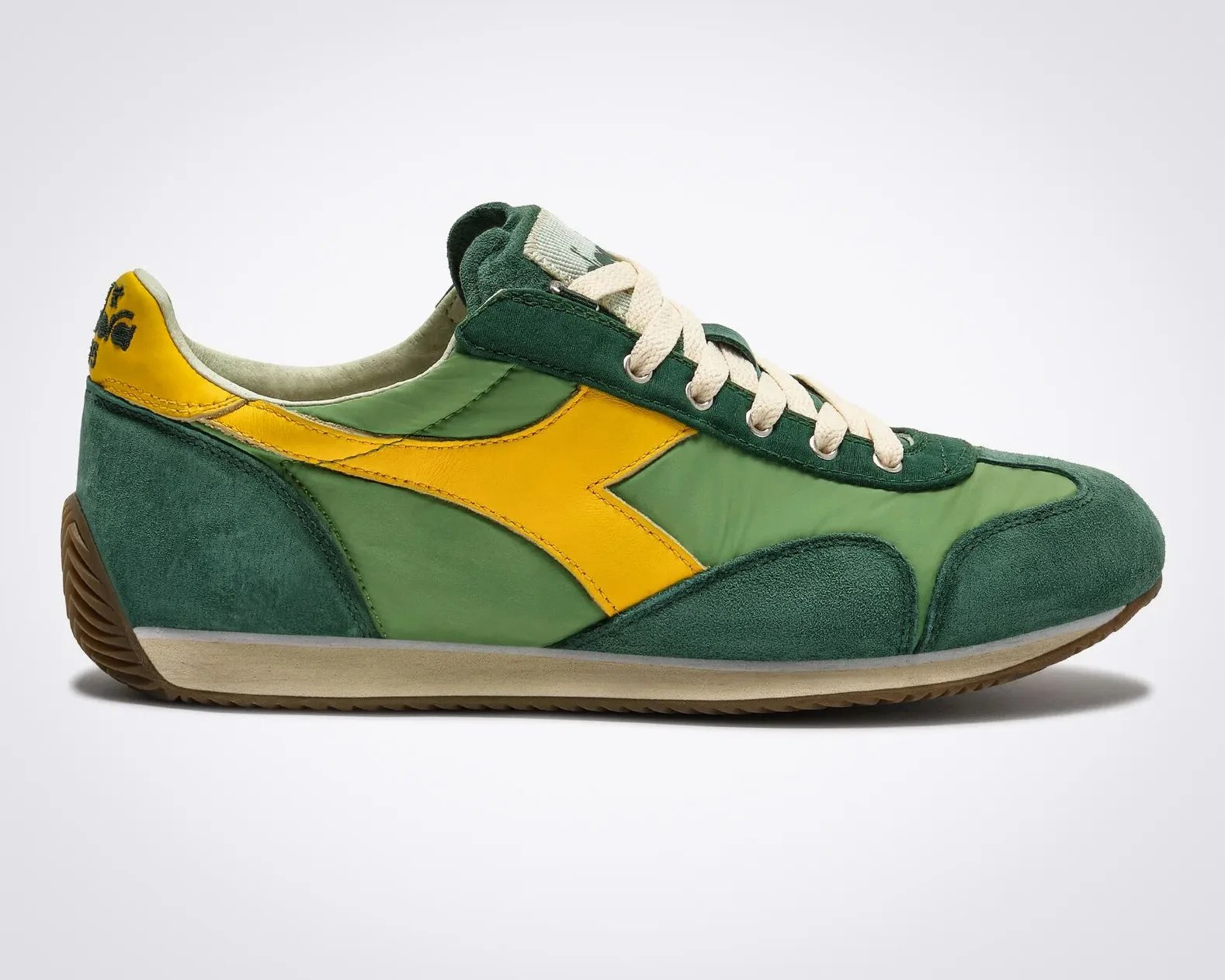 Green and yellow suede and nylon sneaker with white laces and brown rubber sole.
