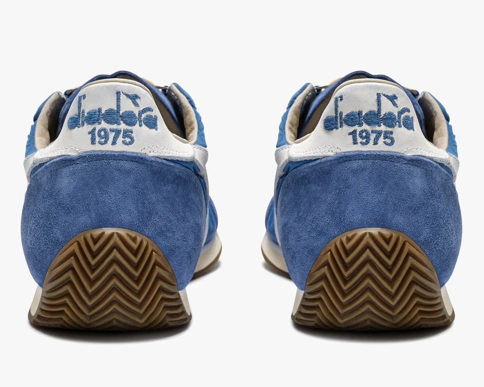 Pair of blue suede sneakers with white heel tabs embroidered with "diadora 1975" and brown rubber soles.
