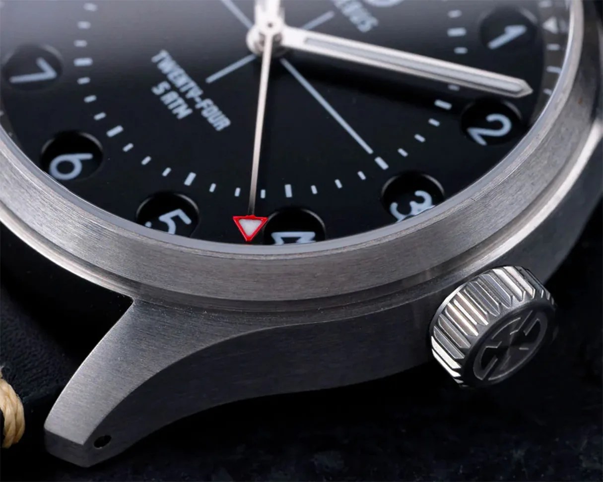 Close-up of a stainless steel watch case with a black dial, white numerals, and a red-tipped second hand.