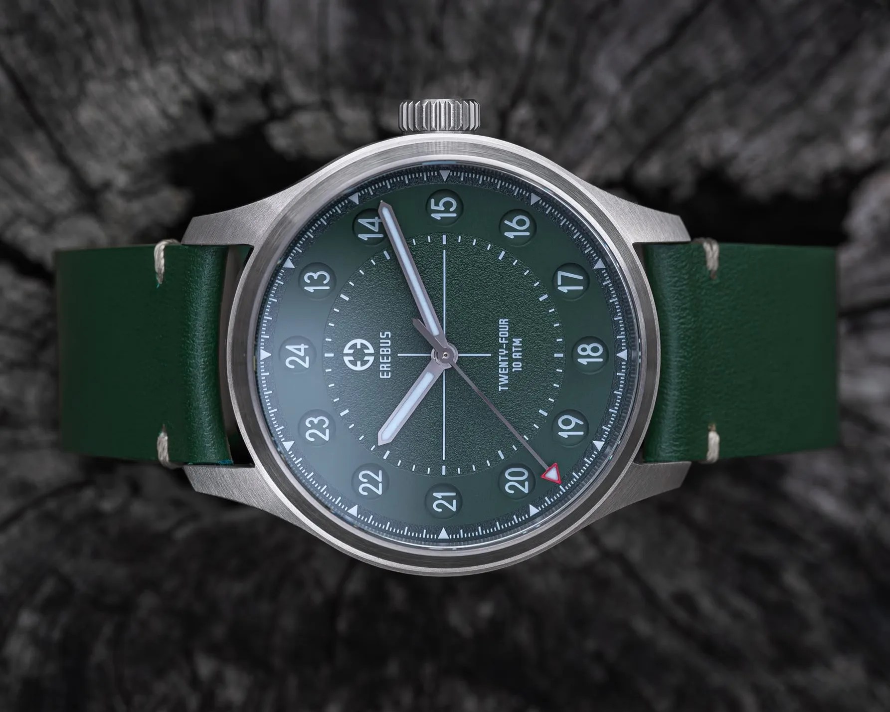 Silver metal wristwatch with a green dial featuring 24-hour markers and a matching green leather strap.