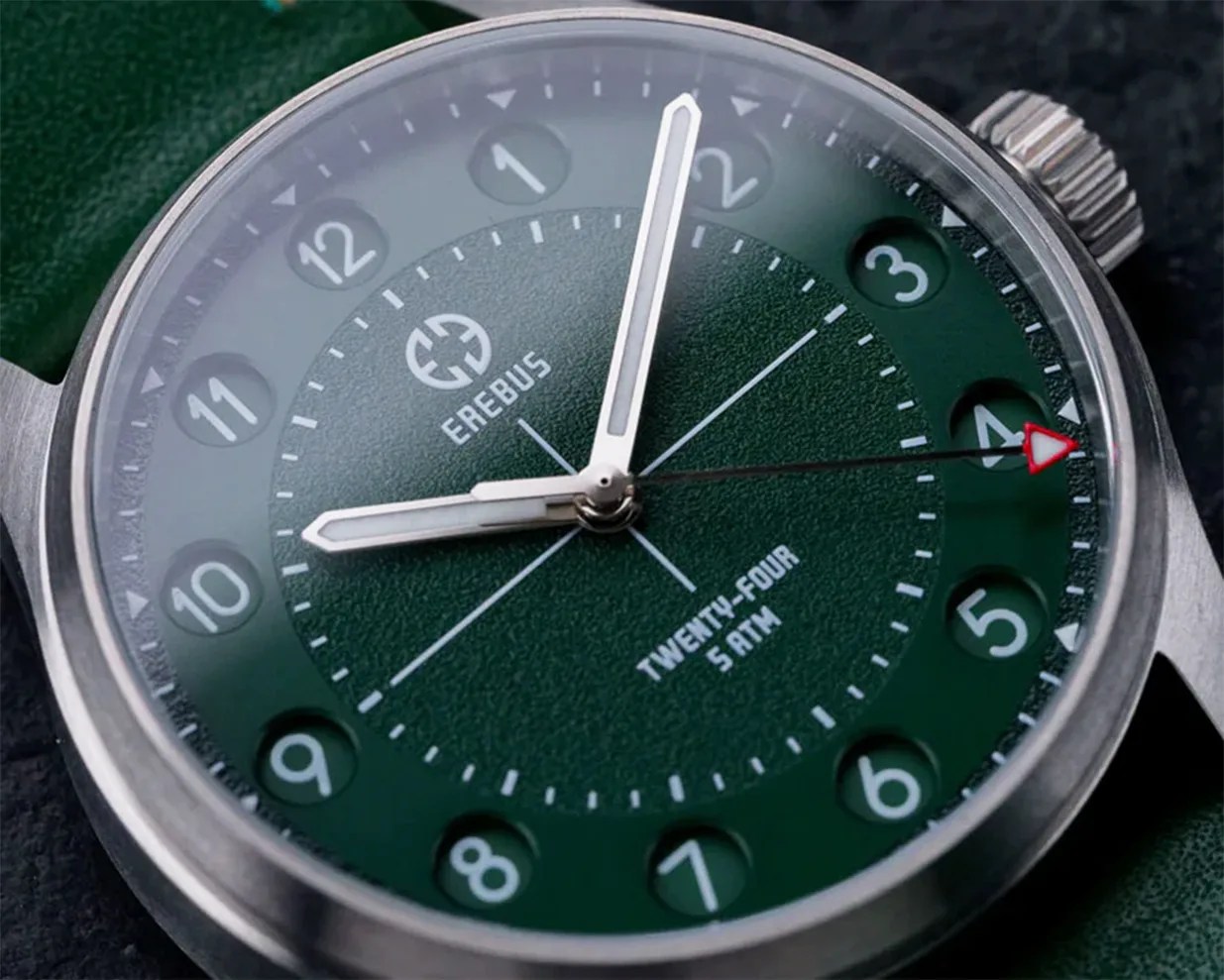 Close-up of a green Erebus wristwatch with white hour markers, silver hands, and a red-tipped second hand.