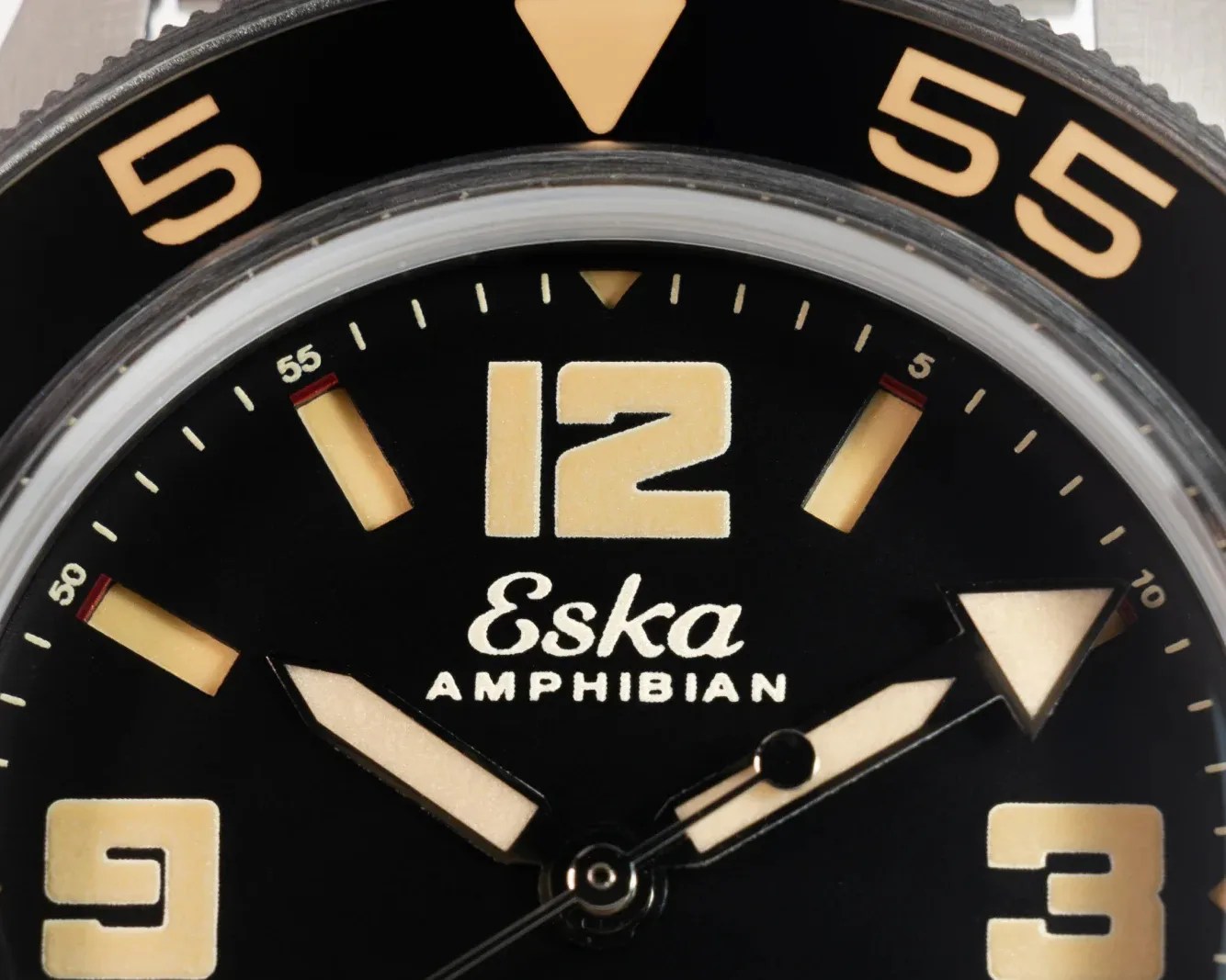 Close-up of black Eska Amphibian watch face with large beige numerals and luminous hands.