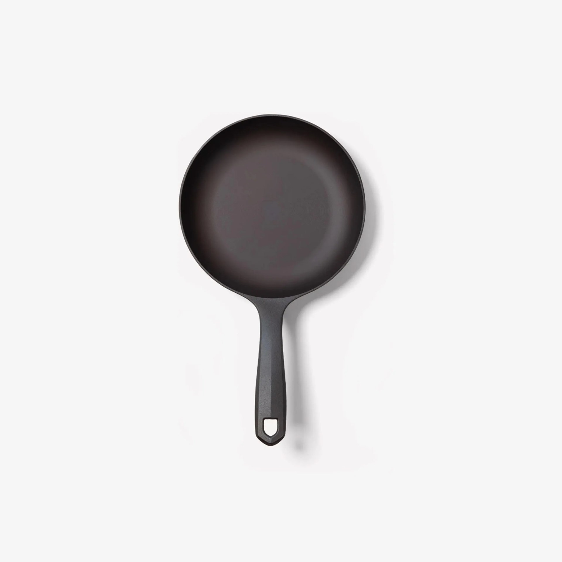 Black nonstick frying pan with a straight handle and hanging hole on a white background.