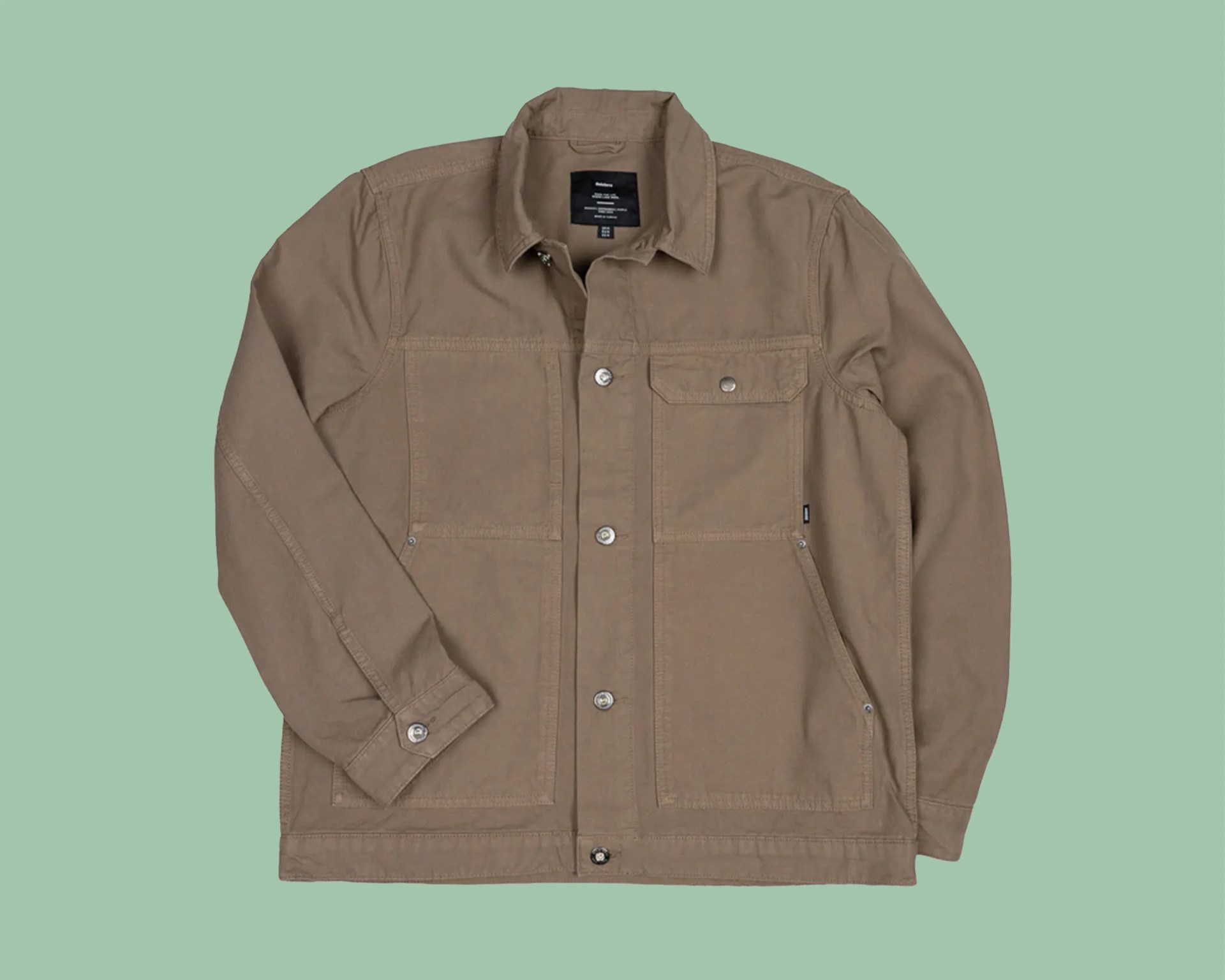 Light brown button-up jacket with multiple front pockets laid flat on a green background.