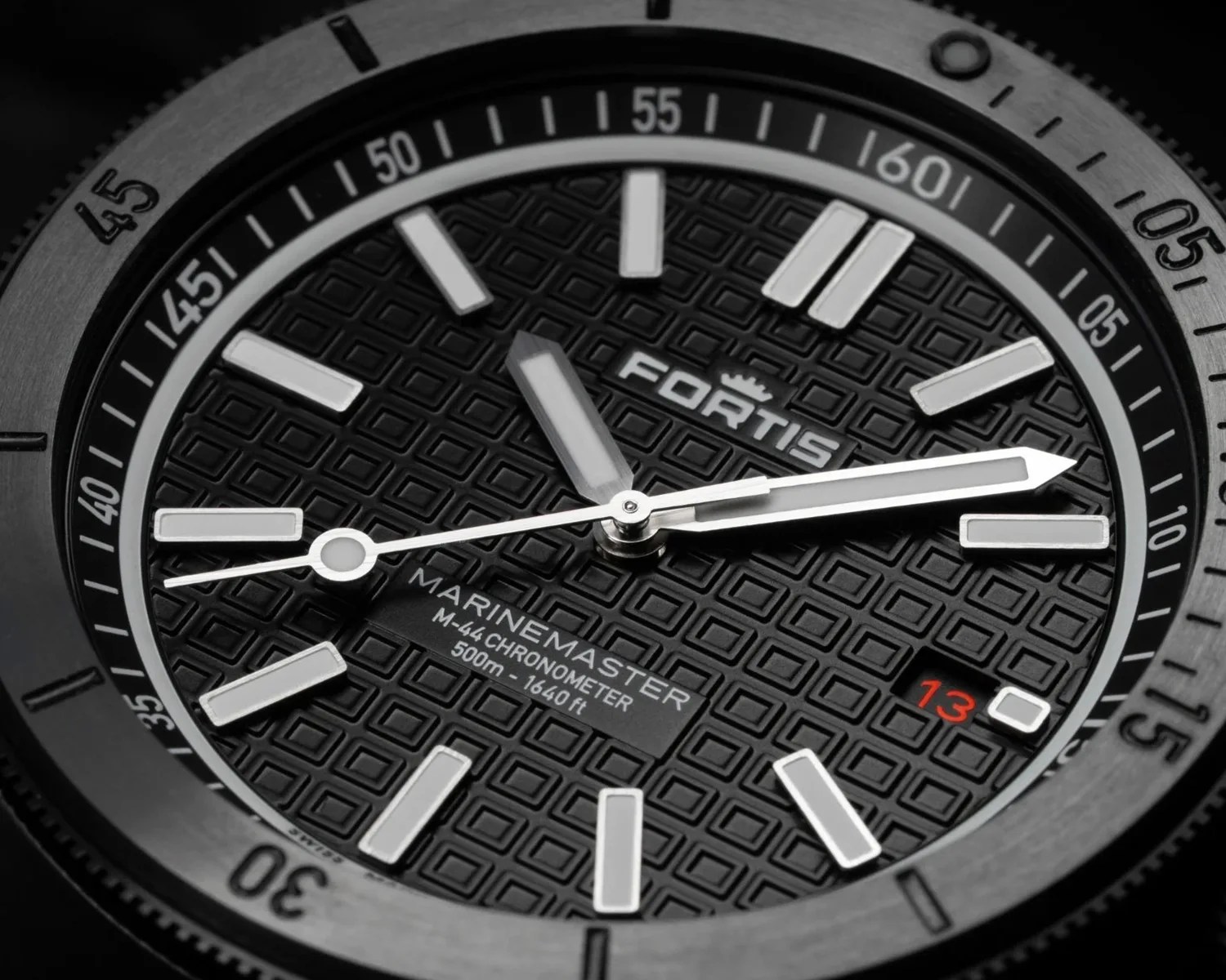 Close-up of a Fortis Marinemaster M-44 Chronometer watch face with black textured dial and white markers.