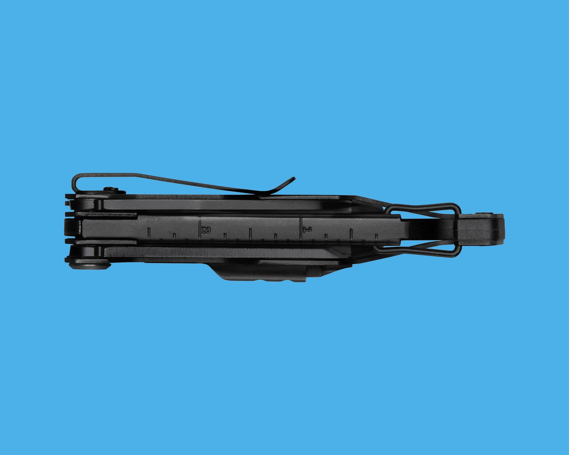 Black folded multitool with a clip and ruler markings on a blue background.