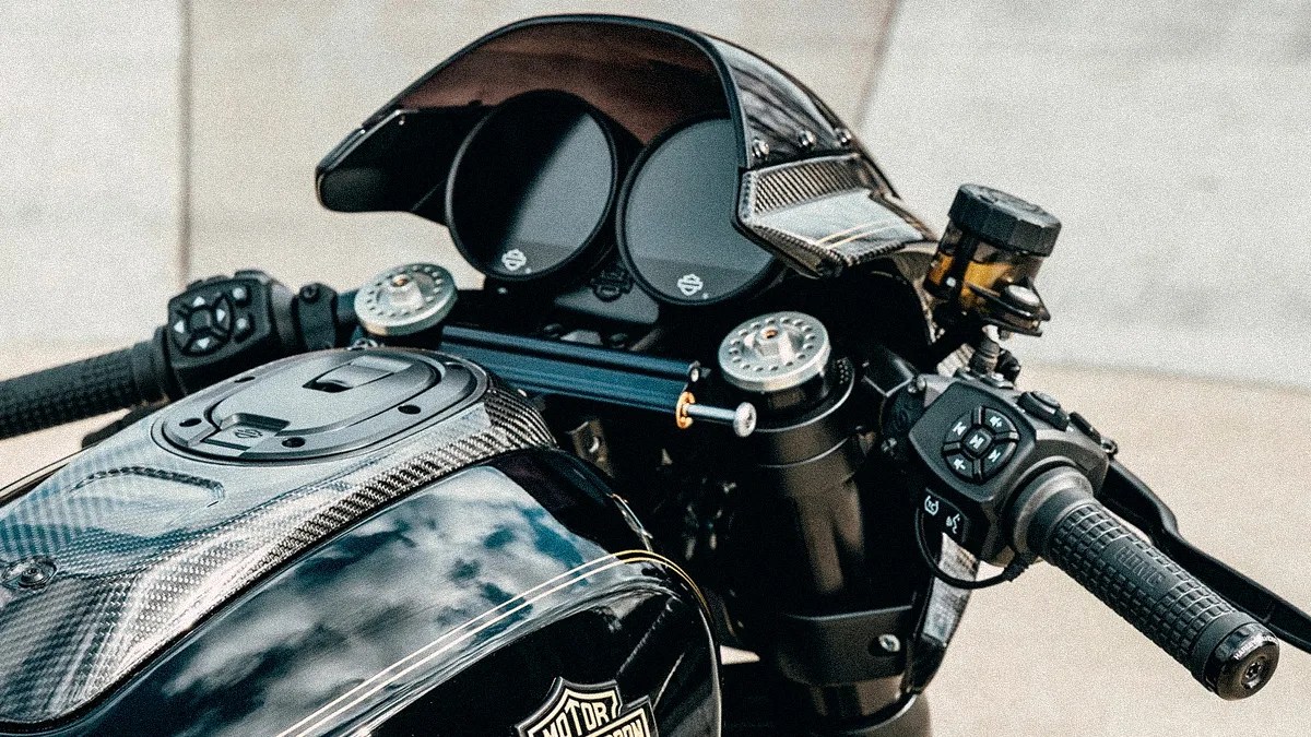 Close-up of a black Harley-Davidson motorcycle dashboard with carbon fiber details and dual round gauges.