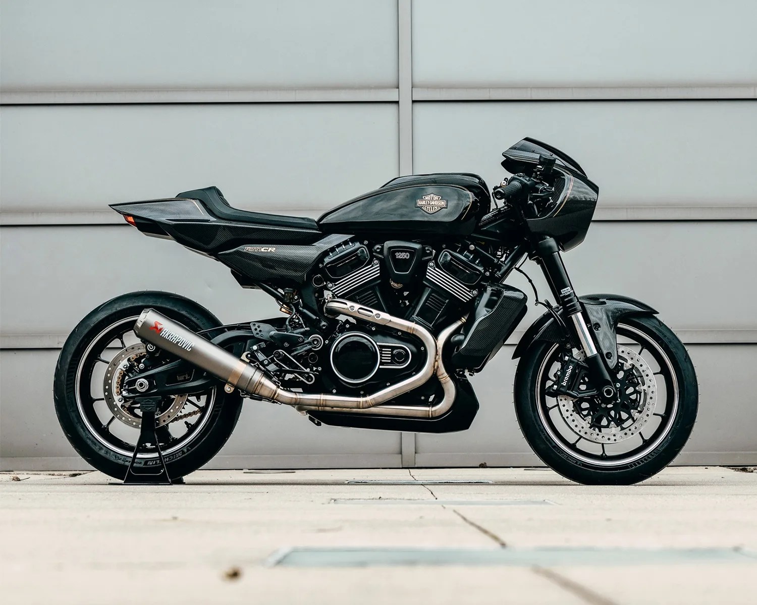 Black Harley-Davidson motorcycle with carbon fiber body panels and Akrapovic exhaust on a stand.