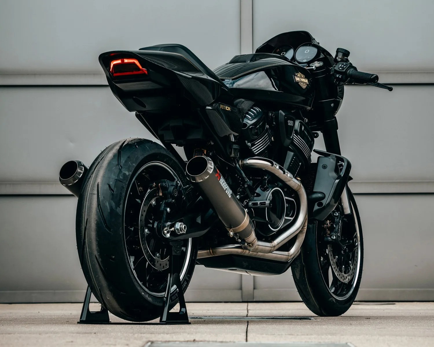Black Harley-Davidson motorcycle with dual Akrapovič exhaust pipes on rear stands.