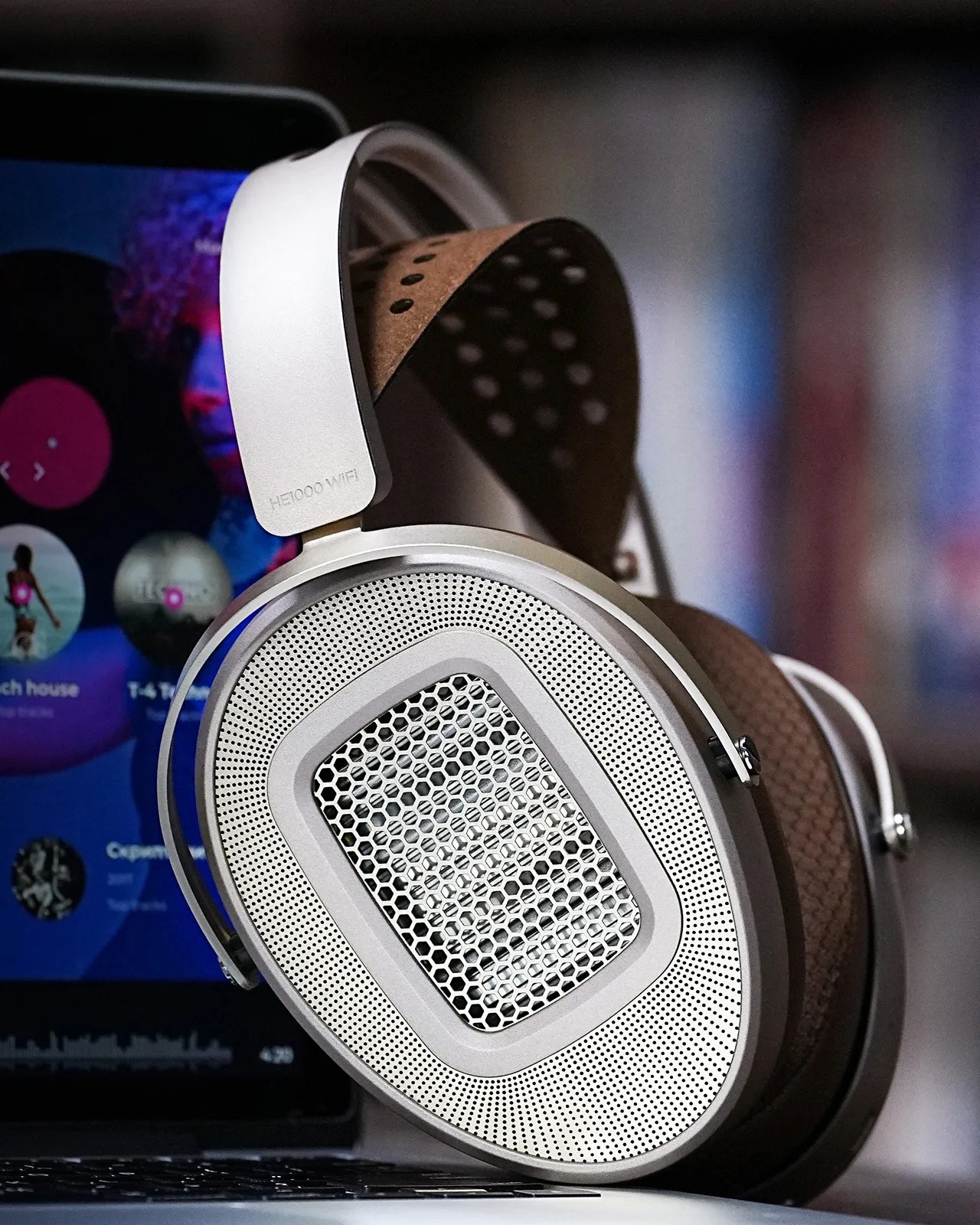 Silver open-back headphones with brown perforated leather headband resting on a laptop keyboard.
