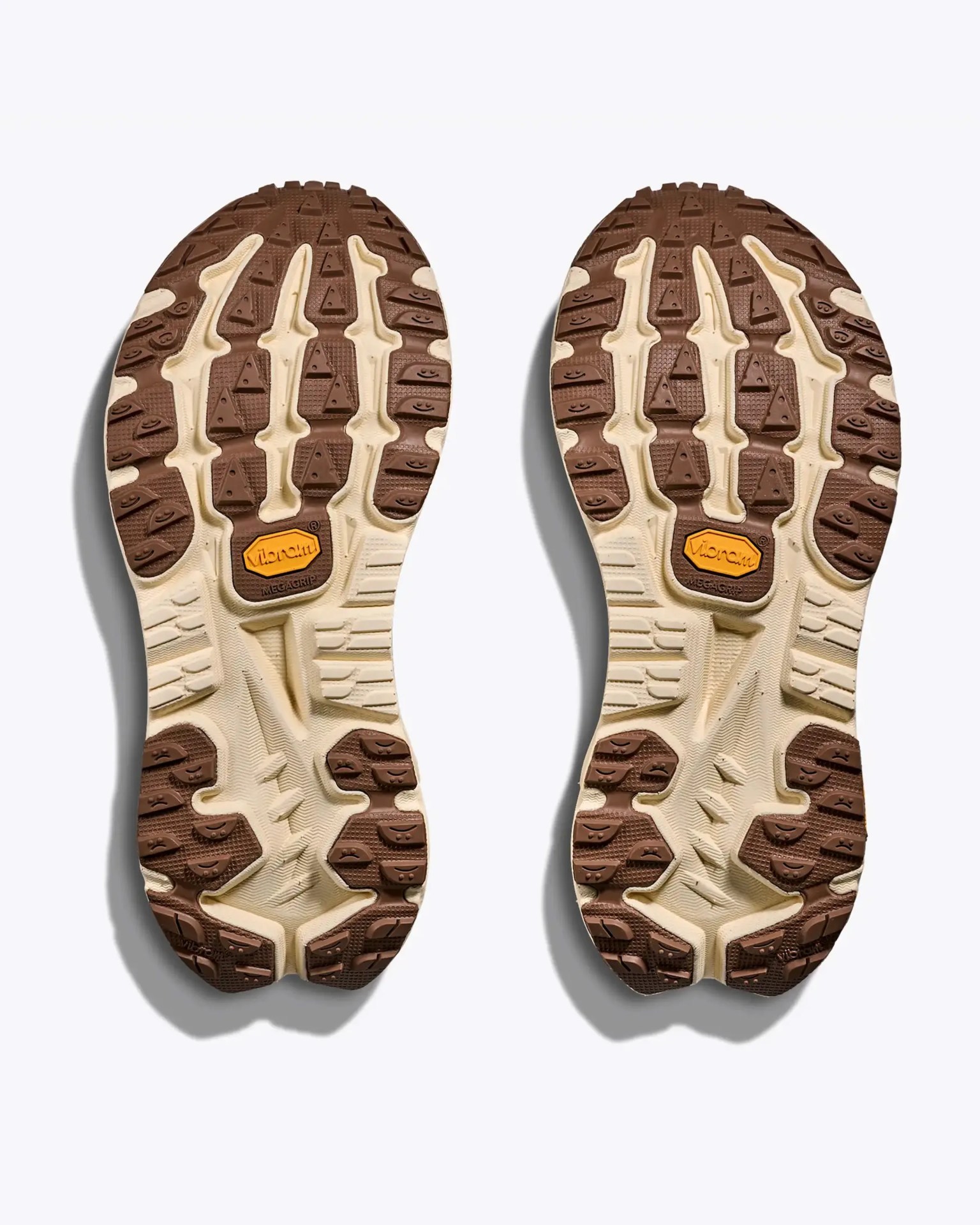 Pair of beige and brown Vibram Megagrip shoe soles with textured tread pattern shown from the bottom.