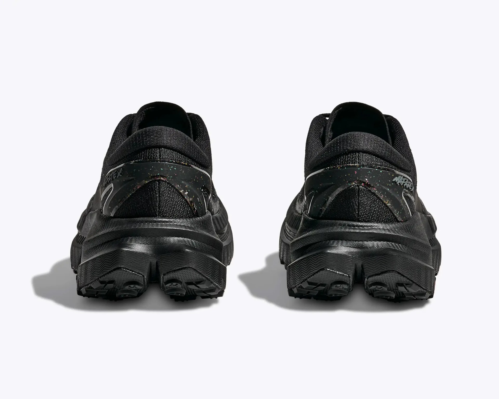 Pair of black athletic shoes shown from the back with textured soles and speckled heel overlays.