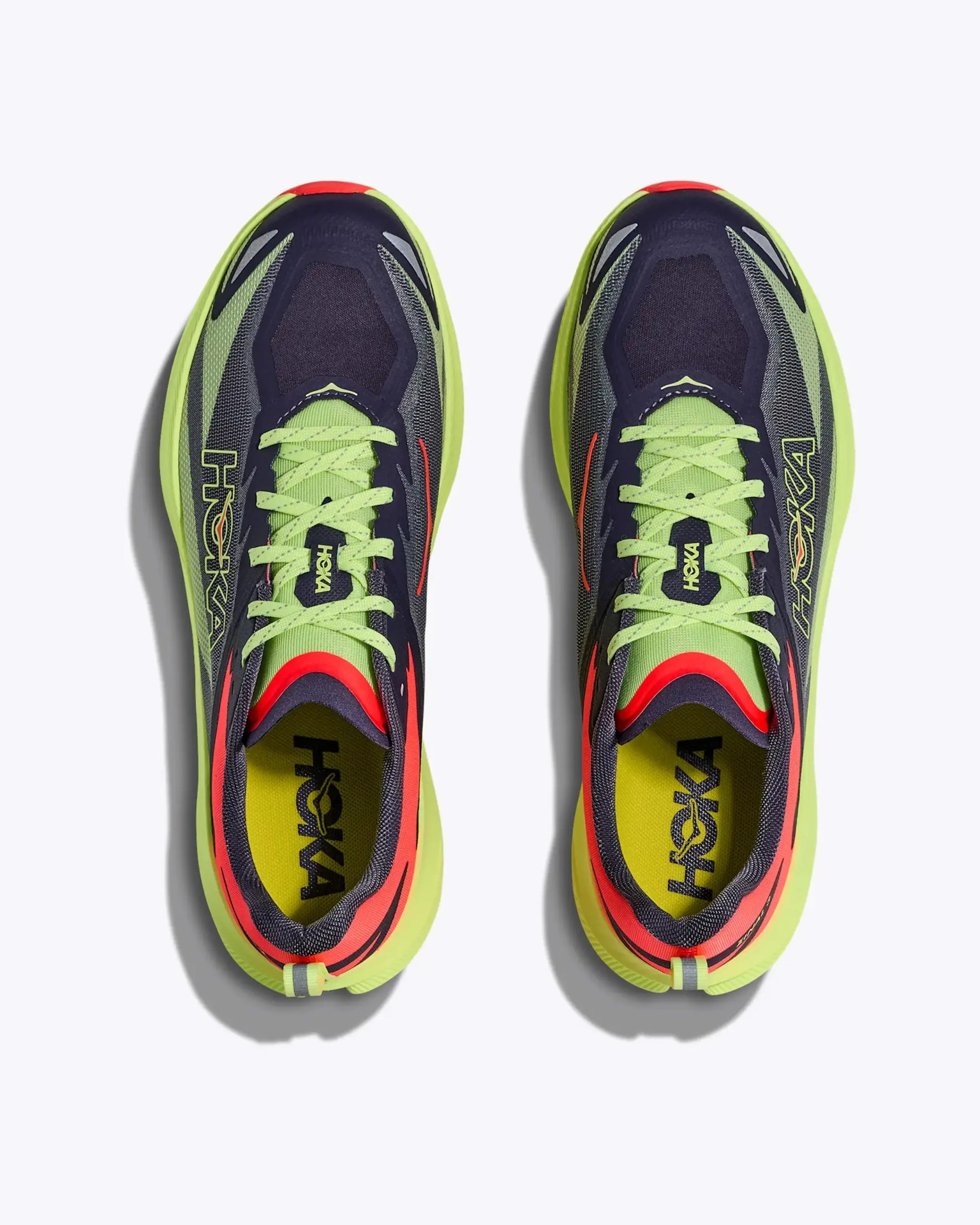 Pair of neon green and black HOKA running shoes with red accents viewed from above.