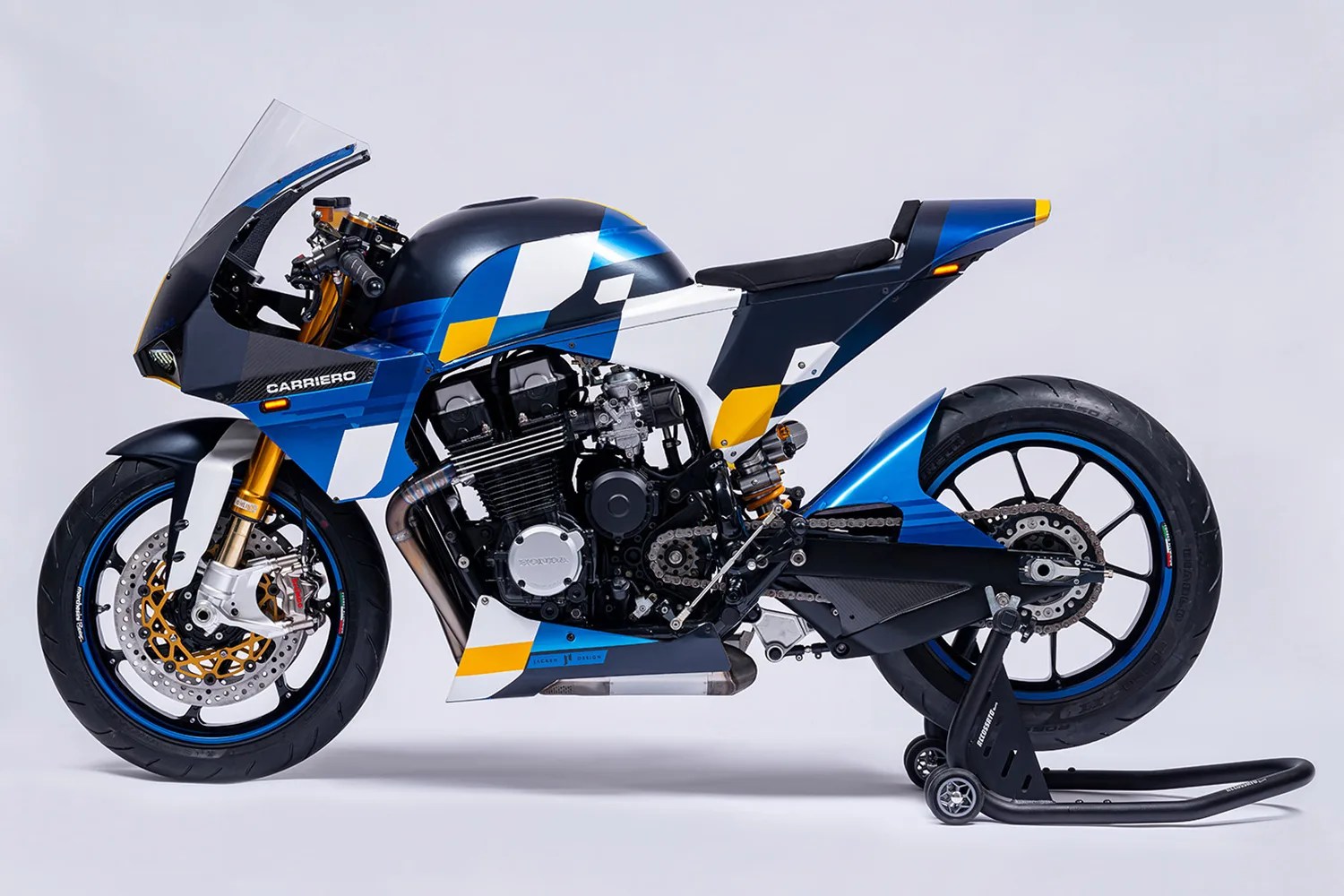Blue, white, and yellow sport motorcycle with black engine and carbon fiber accents on a rear stand.