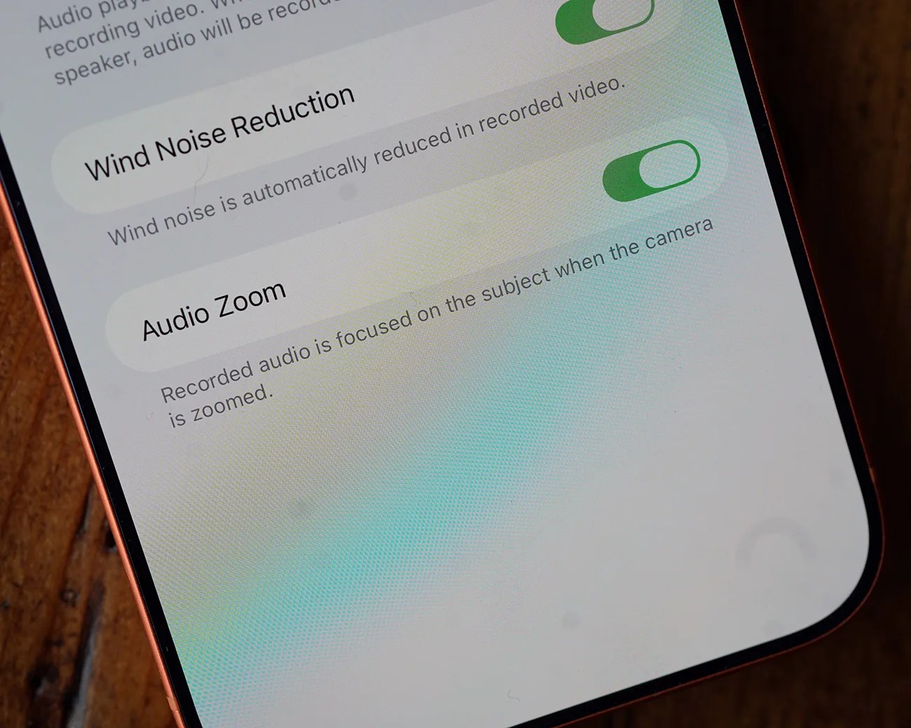 Smartphone screen showing enabled settings for "Wind Noise Reduction" and "Audio Zoom" in a video recording app.