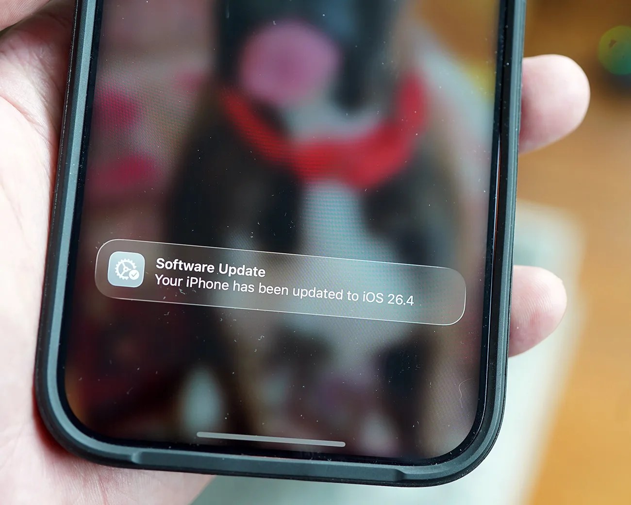 Close-up of a smartphone screen showing a notification that the iPhone has been updated to iOS 26.4.
