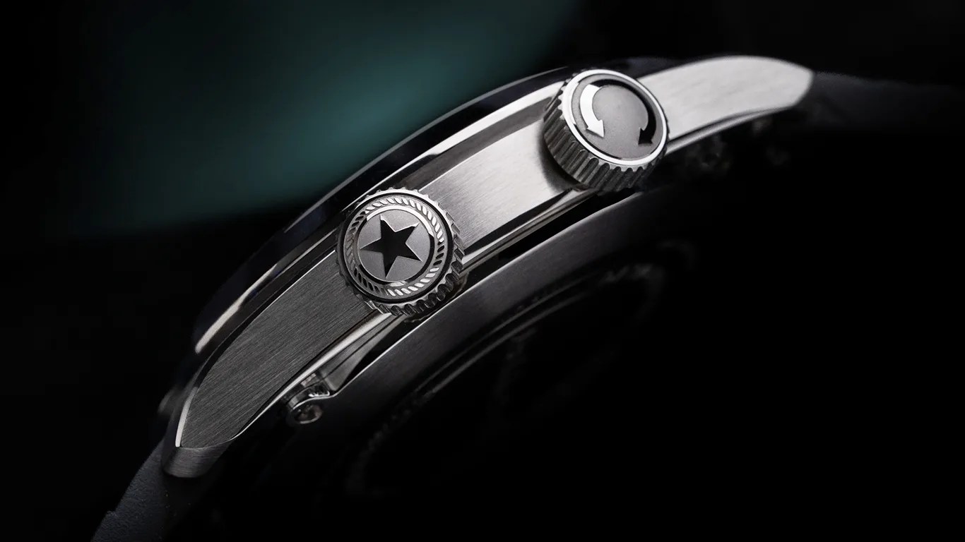Close-up of a stainless steel watch side with two crowns, one featuring a star and the other with circular arrows.