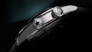 Close-up of a stainless steel watch side with two crowns, one featuring a star and the other with circular arrows.