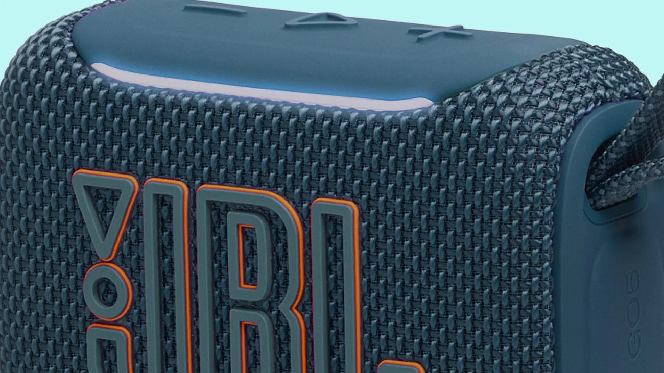 Close-up of a blue JBL portable Bluetooth speaker with textured fabric and orange-edged logo.