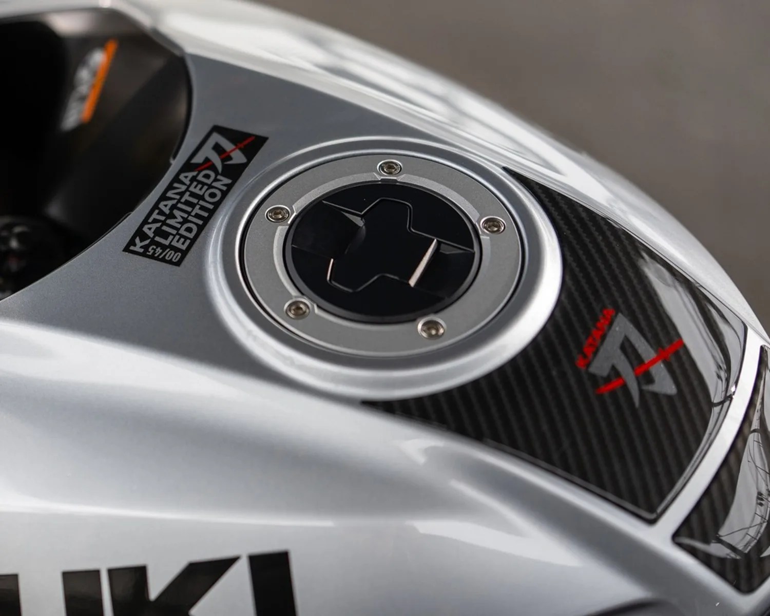 Silver Suzuki Katana motorcycle fuel tank with black carbon fiber panel and "Katana Limited Edition" decal.