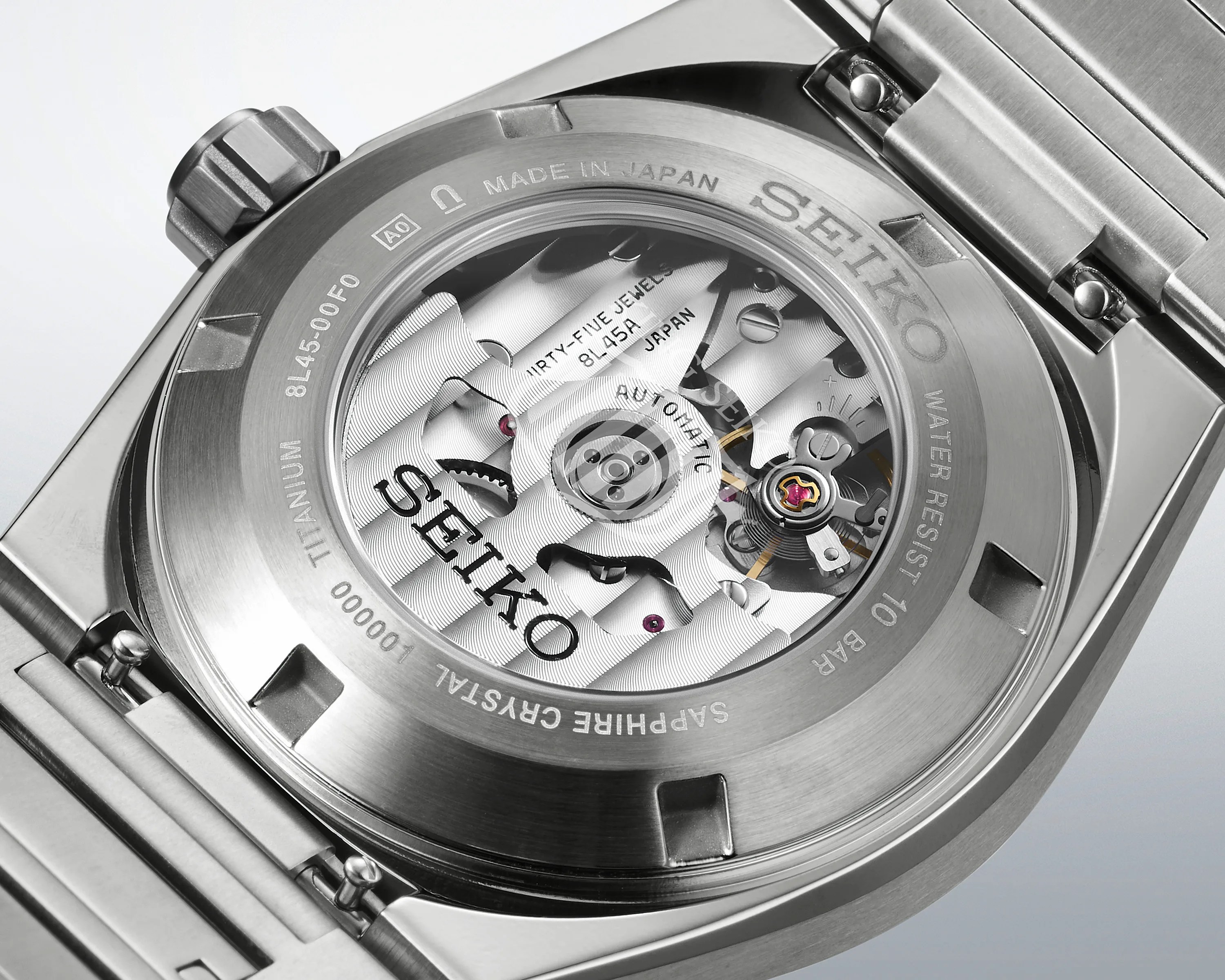 Close-up of the back of a Seiko titanium watch showing the automatic movement through a sapphire crystal case back.