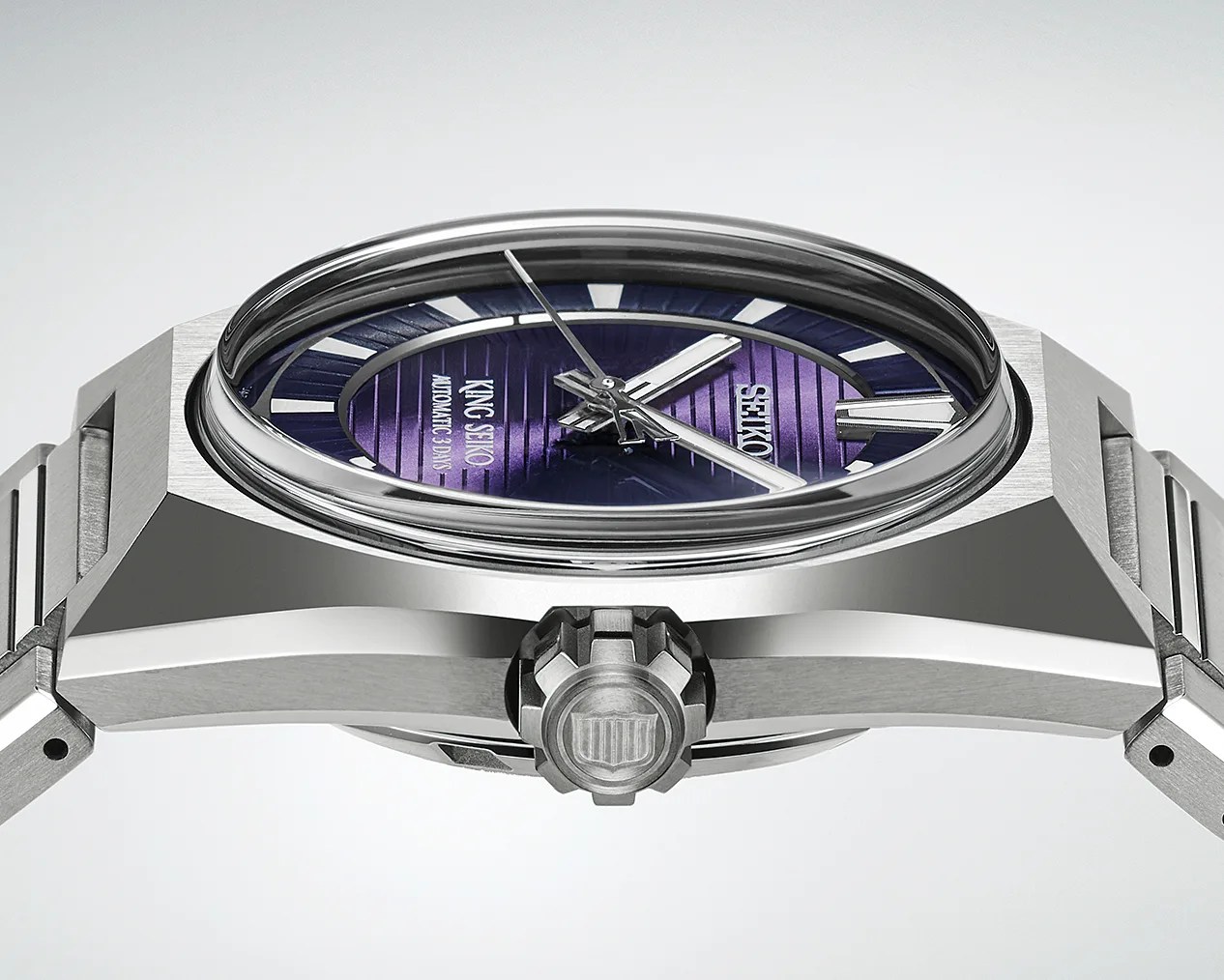 Close-up of a stainless steel King Seiko watch with a purple dial and silver hands, showing the crown and side profile.