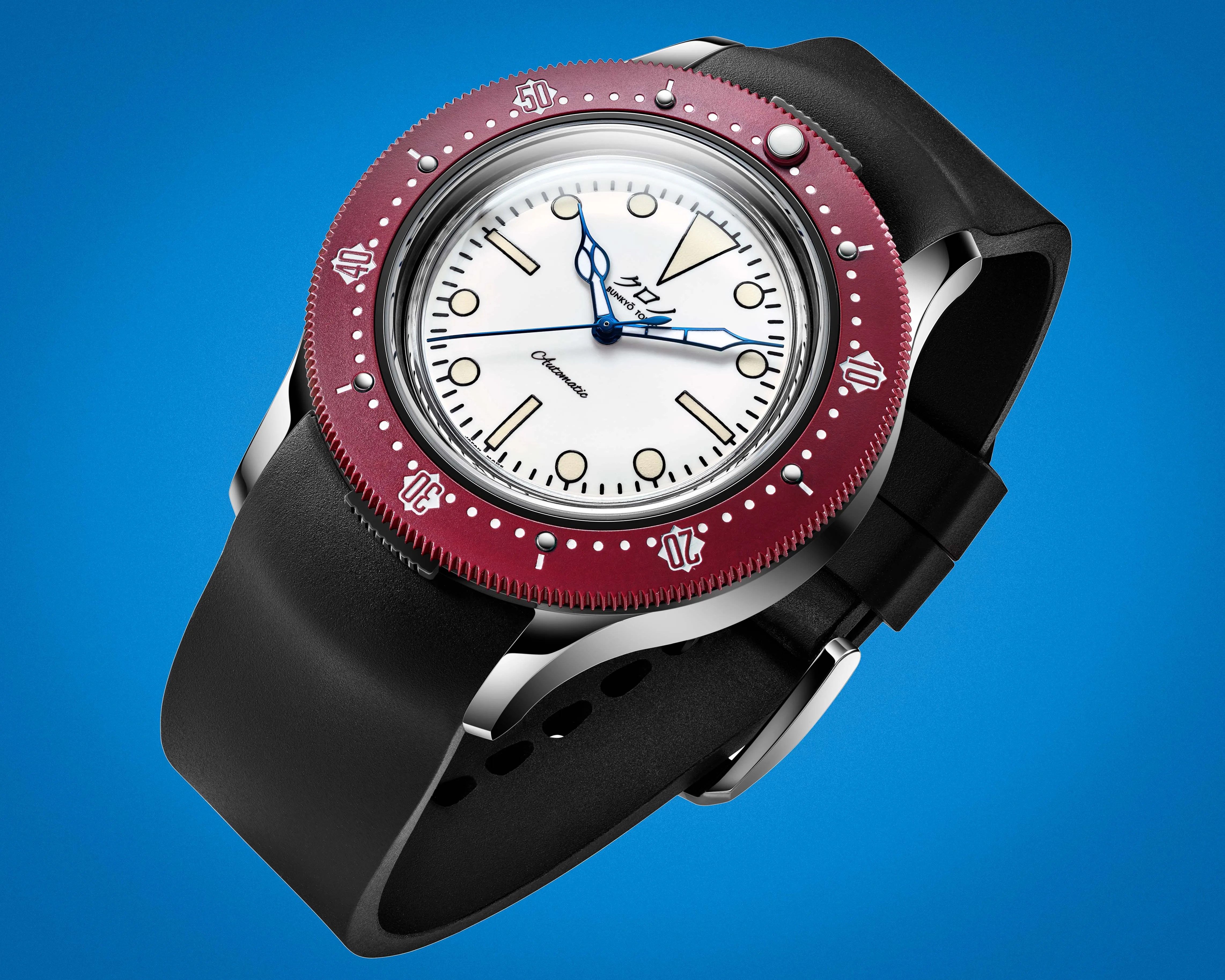 Diver-style wristwatch with a white dial, blue hands, burgundy bezel, and black rubber strap on a blue background.