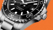 Close-up of a stainless steel Longines HydroConquest automatic watch with black dial and rotating bezel on an orange background.