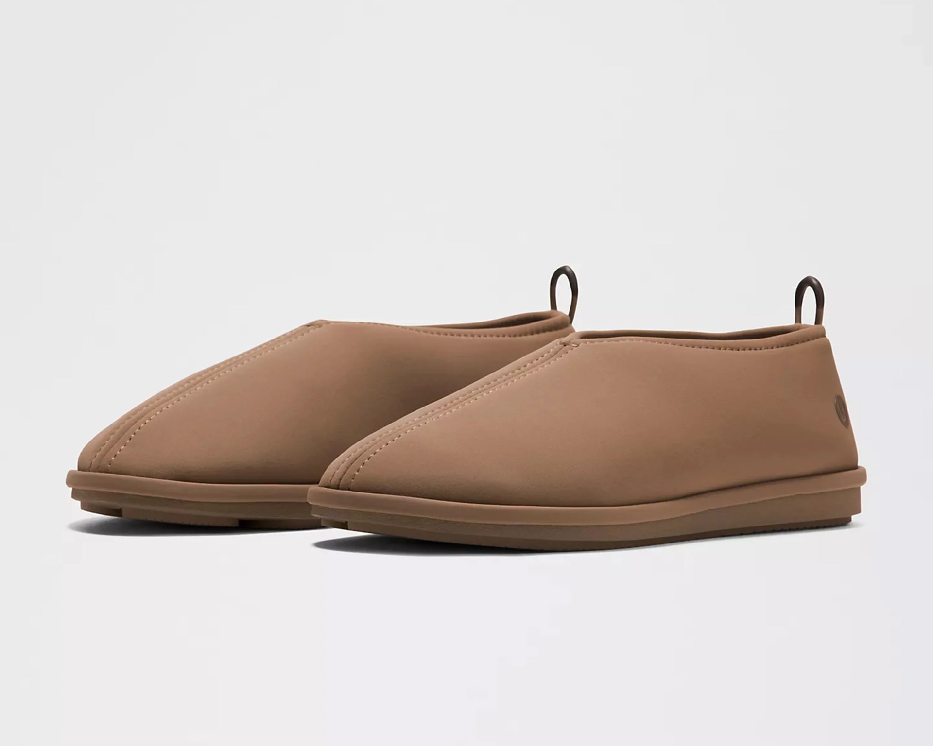 Pair of brown slip-on shoes with rounded toes and pull tabs at the heel on a white background.