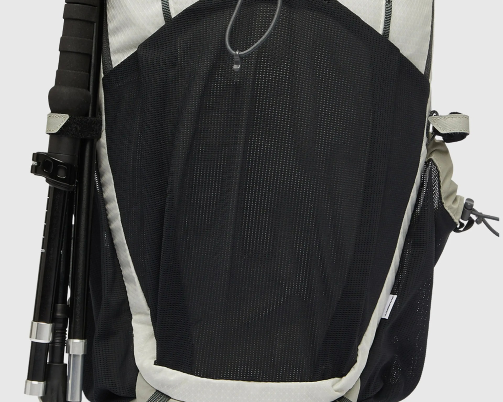 Close-up of a black and gray mesh backpack pocket with a black trekking pole secured on the side.