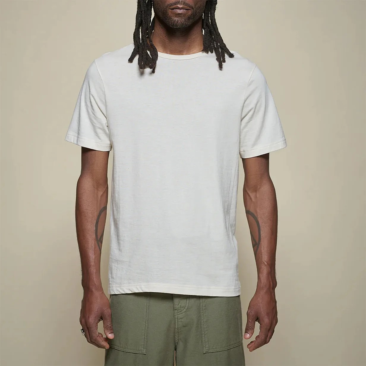 Off-white short-sleeve crew neck t-shirt worn by a person with olive green pants.