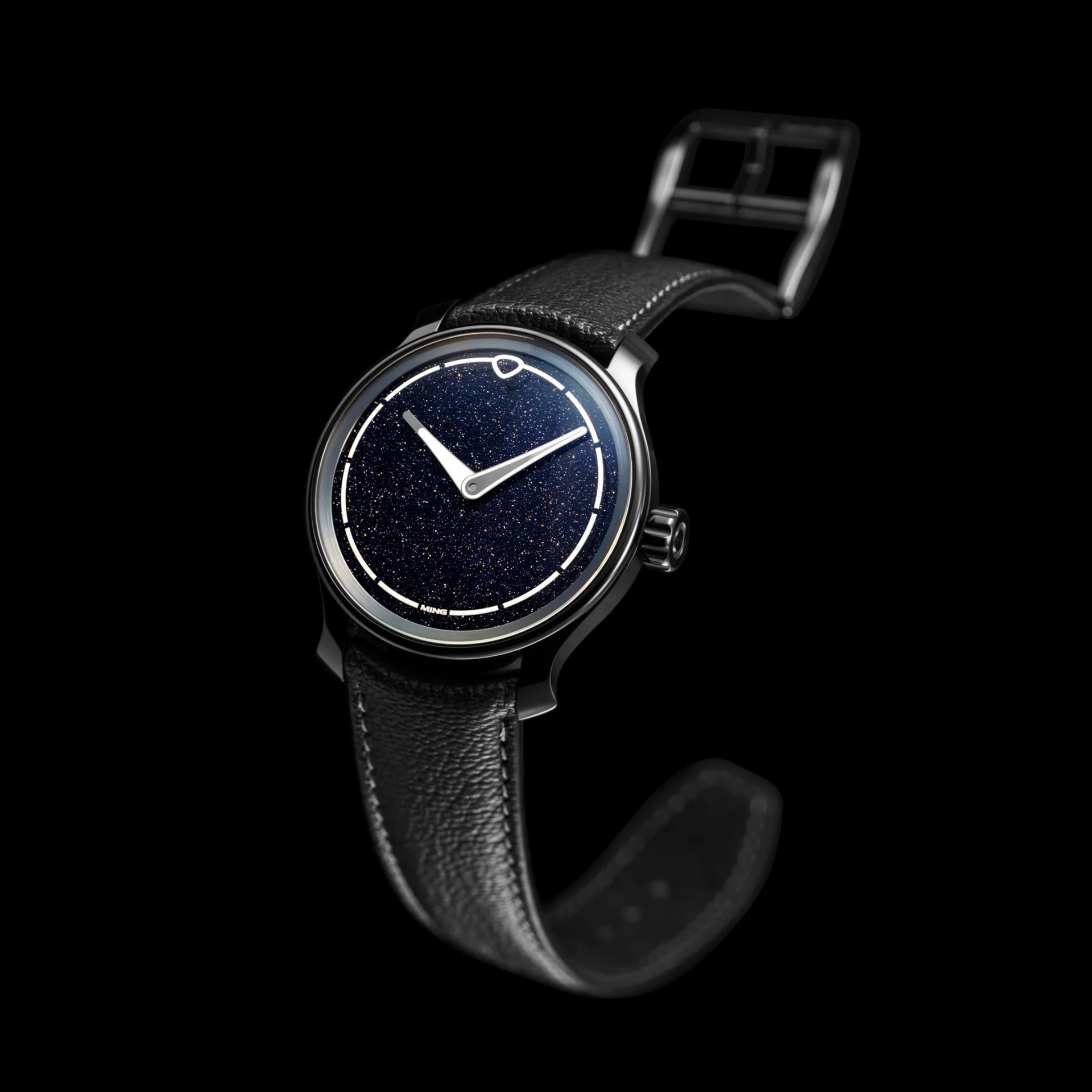 Black leather strap wristwatch with a sparkling dark blue dial and silver hands on a black background.