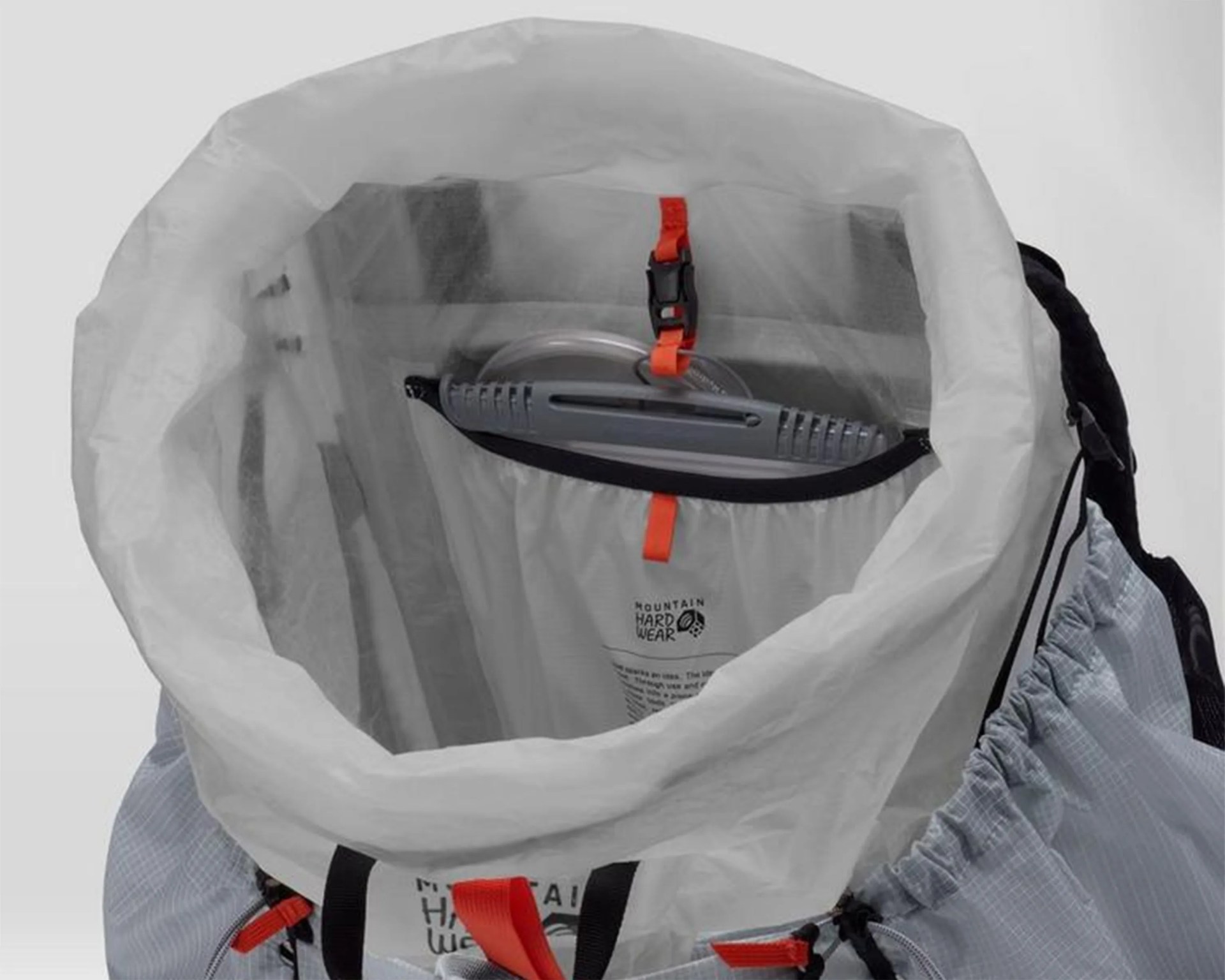 Top view of a gray Mountain Hardwear backpack showing a hydration reservoir secured inside with an orange clip.