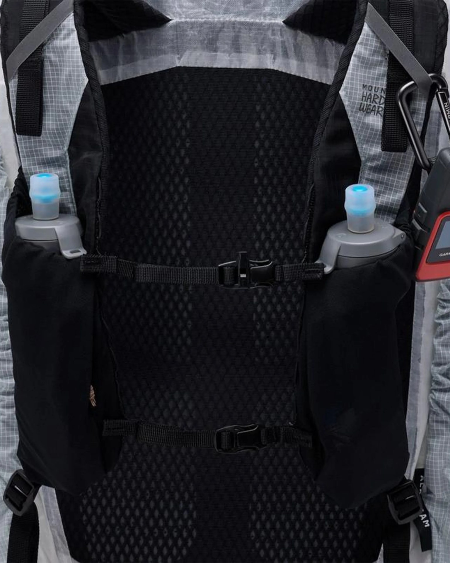 Close-up of a black mesh backpack back panel with two water bottles in side pockets and adjustable chest straps.