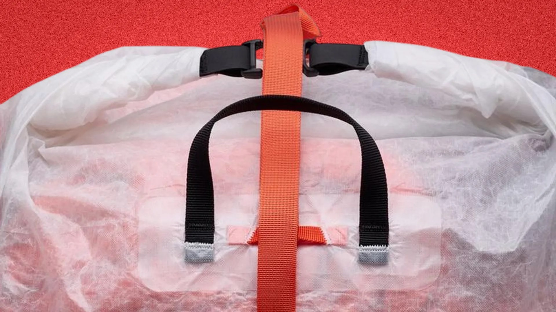 Close-up of a white translucent bag with black and orange straps against a red background.